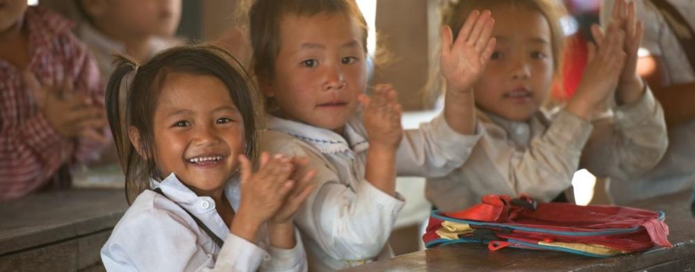 Laoslaiset tytöt taputtaa käsiään yhteen ja hymyilee